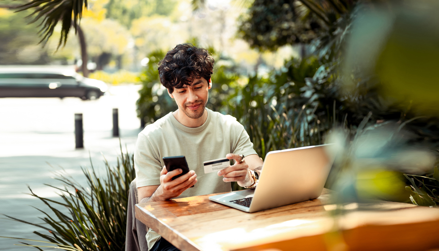 a guy looking at his phone and credit card at an outdoor cafe patio